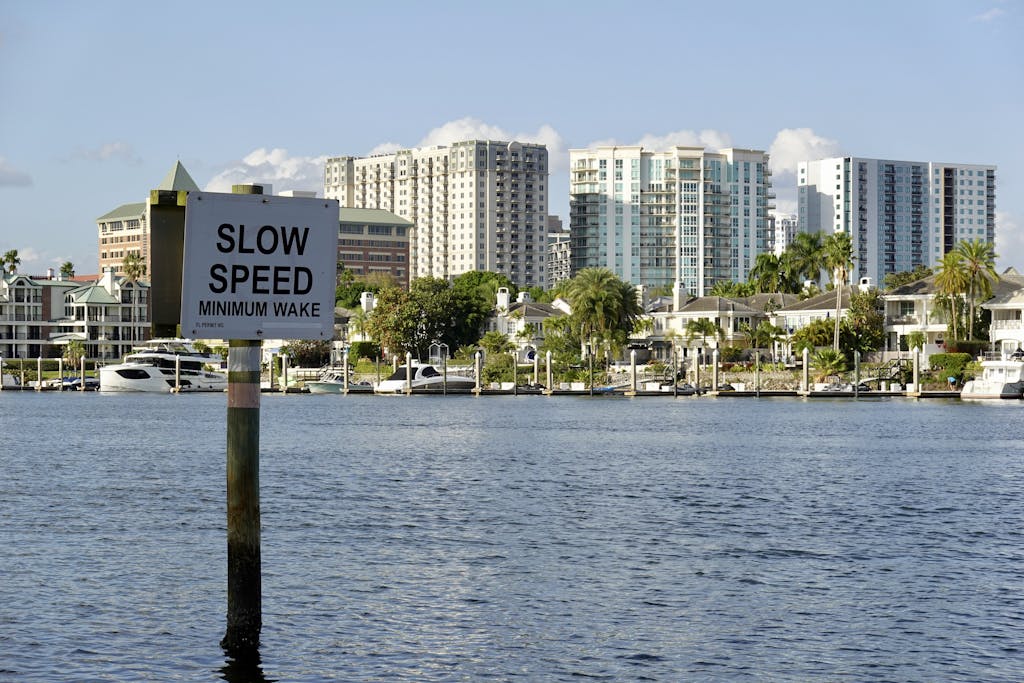 A picturesque view of downtown Tampa's waterfront with a 'Slow Speed' sign and modern buildings in the background.